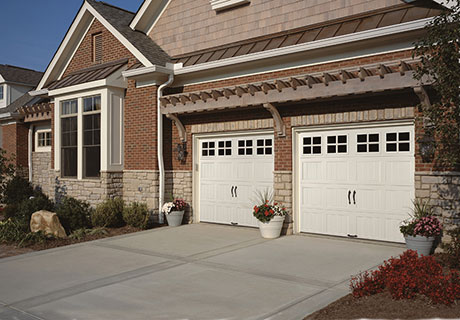 modern stone house with white garage doors